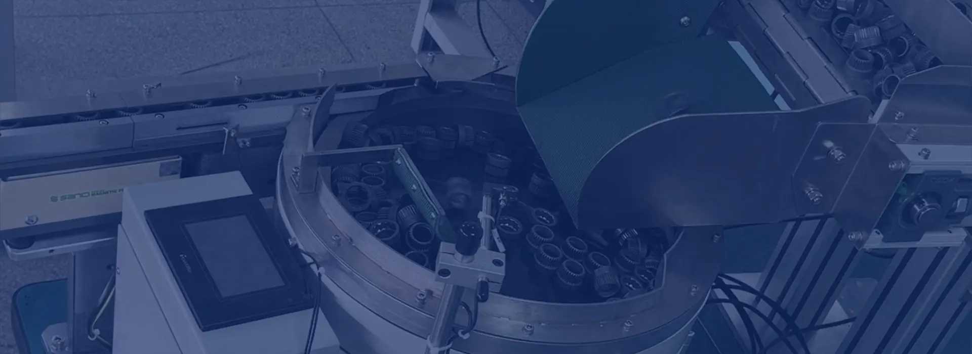 Ring-shaped components in a circular feeder bowl beneath a supply hopper.