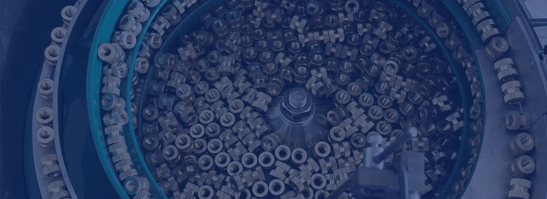 Threaded ring-shaped metal components in a circular feeder bowl.